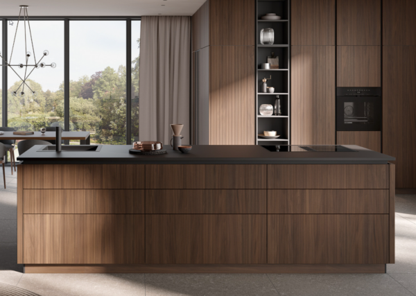 Modern kitchen island with fluted dark wood cabinetry, a matte black countertop, and integrated appliances in a luxury home.